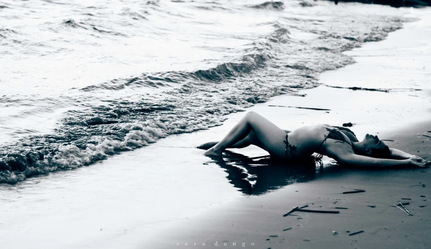 a lady laying on the beach and posing for the camera