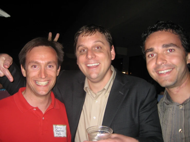 three men standing next to each other holding drinks