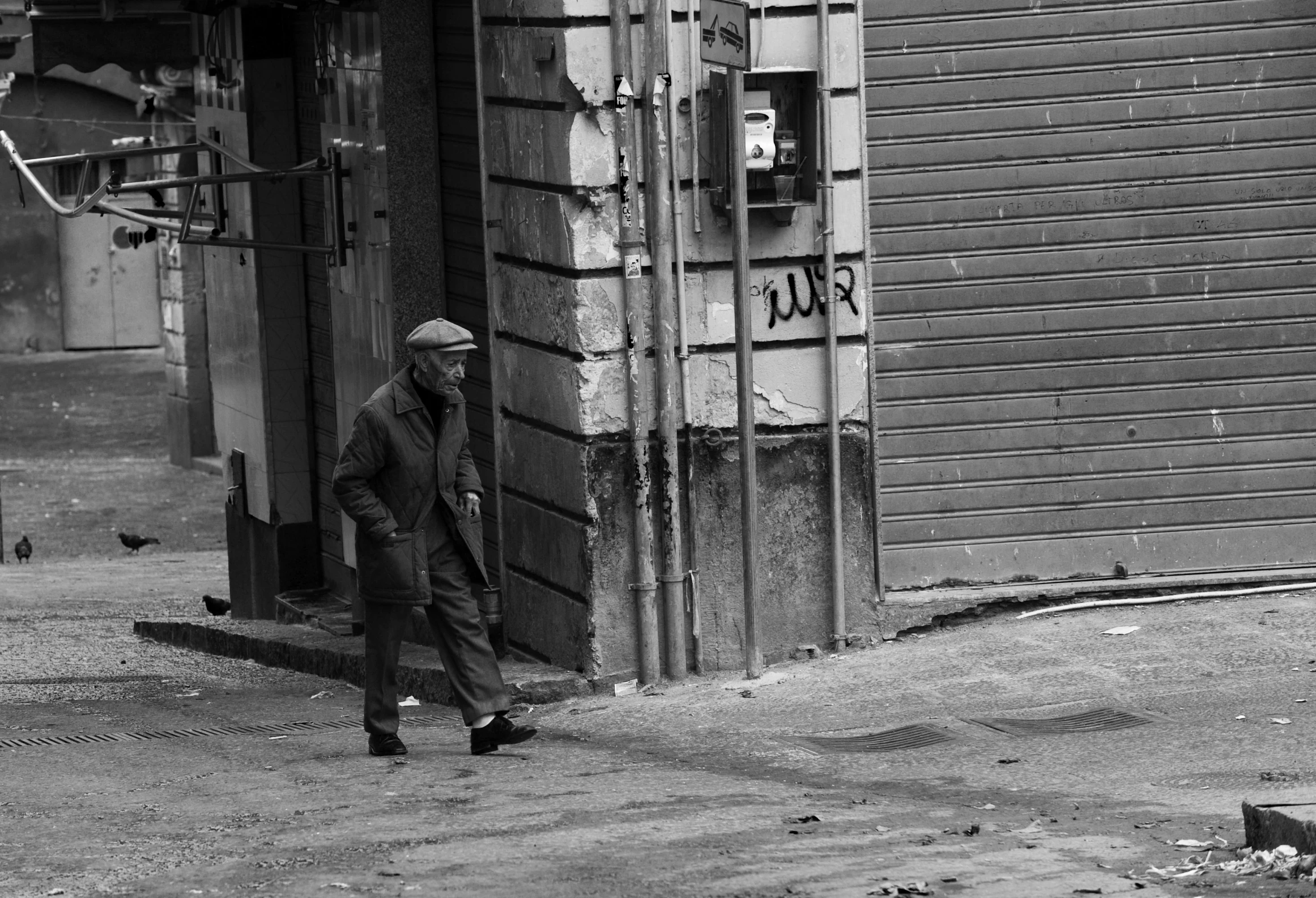 man in all black in front of a small shack