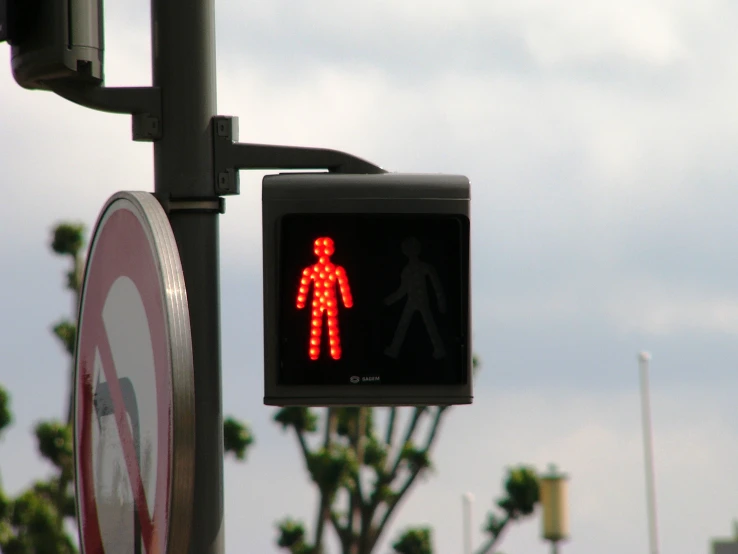 an red pedestrian walk signal next to a street sign