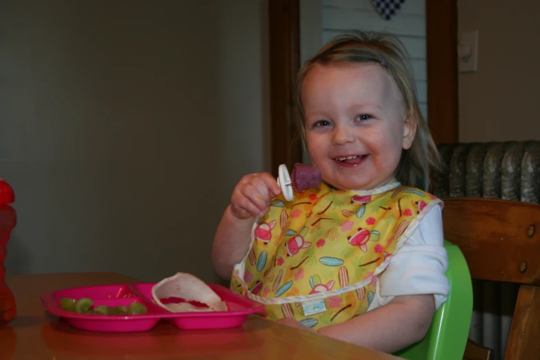 a little girl smiling while eating her food