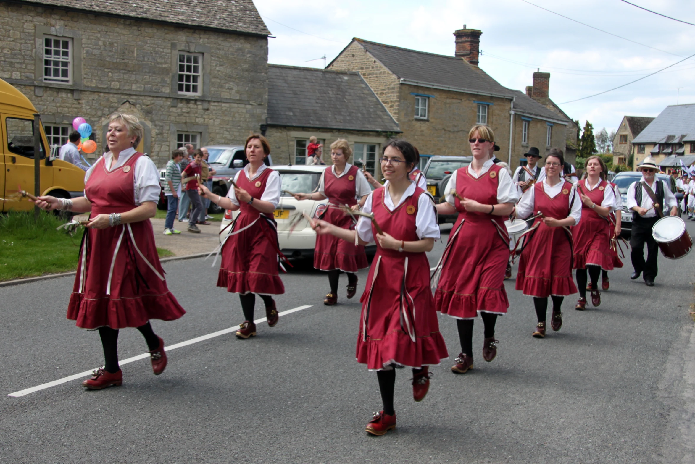 women wearing red skirts, marching on a street