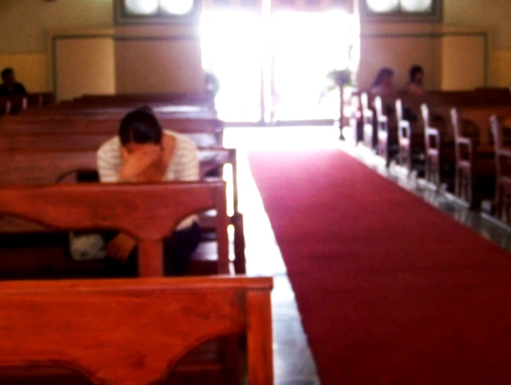 people sitting at benches in the aisle of a church