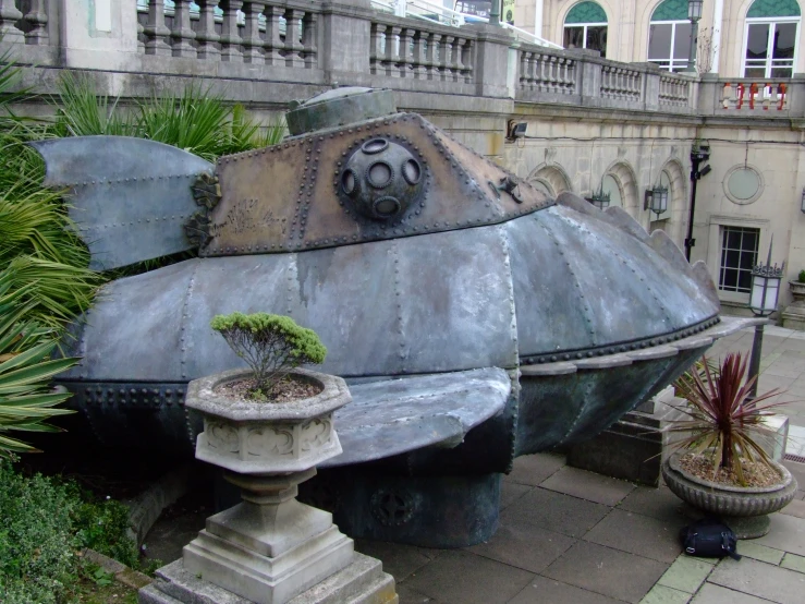 a building made from concrete with plants in the center and a decorative thing to the rear