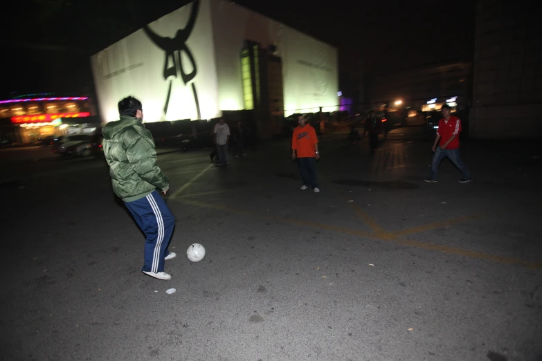 several people standing around playing with a ball in the street