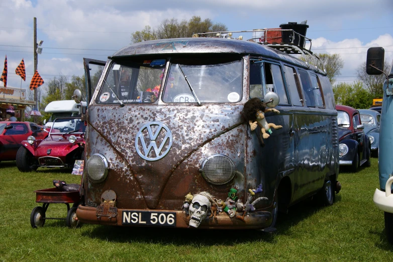an old volkswagen van with stickers parked in grass