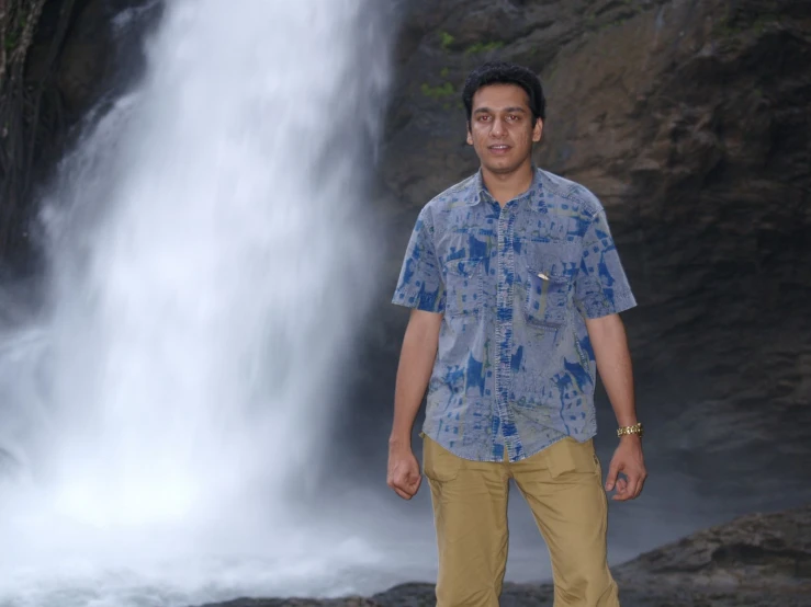 a man standing next to a waterfall with no one around him