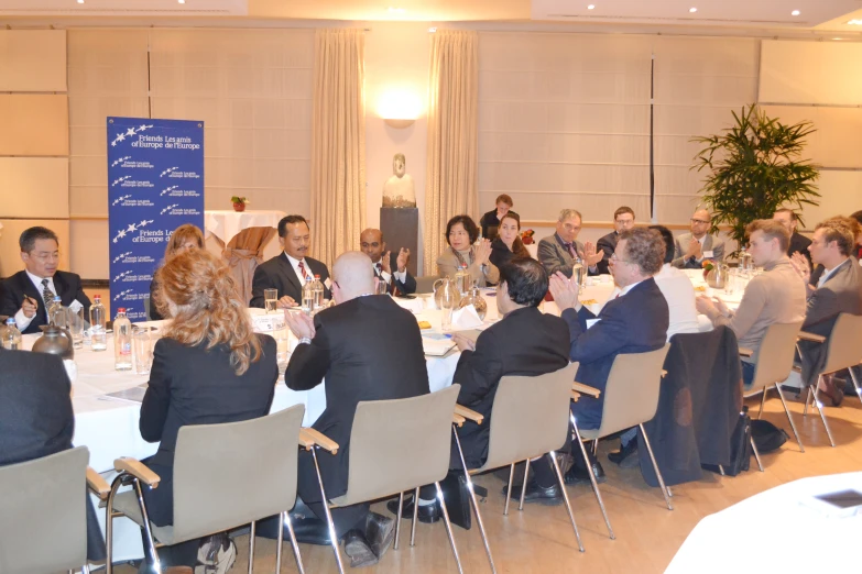 a group of people in suits sitting at a table with drinks