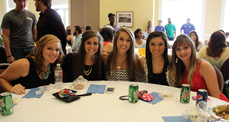 four girls are smiling for the camera while having lunch