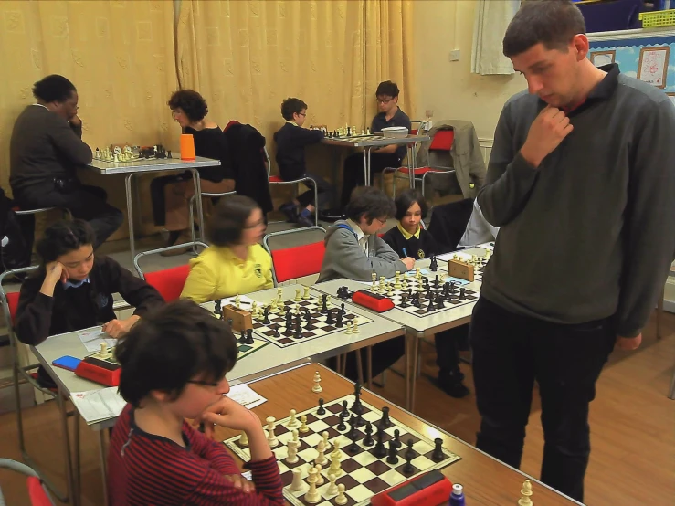 men playing chess at a table in a room with other people