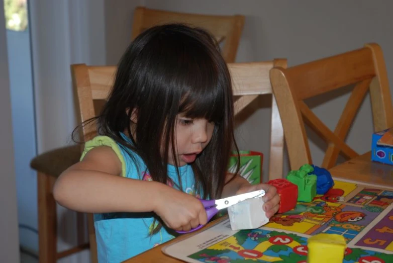 a little girl plays with toys at a table