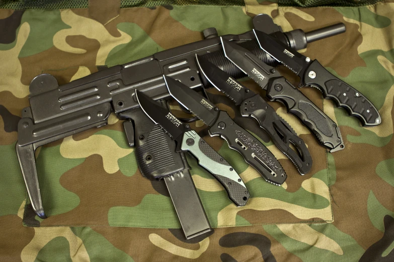 several knives, knives and magazines laid out on a camouflage blanket