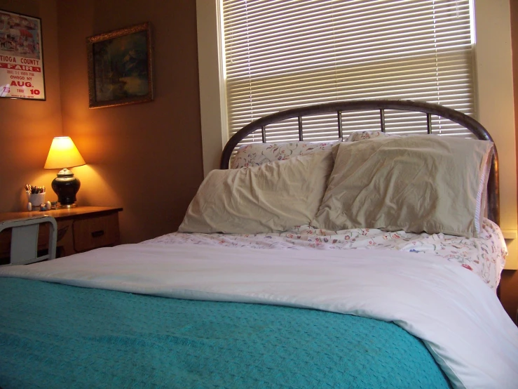 a bed with two pillows on the headboard and a small side table