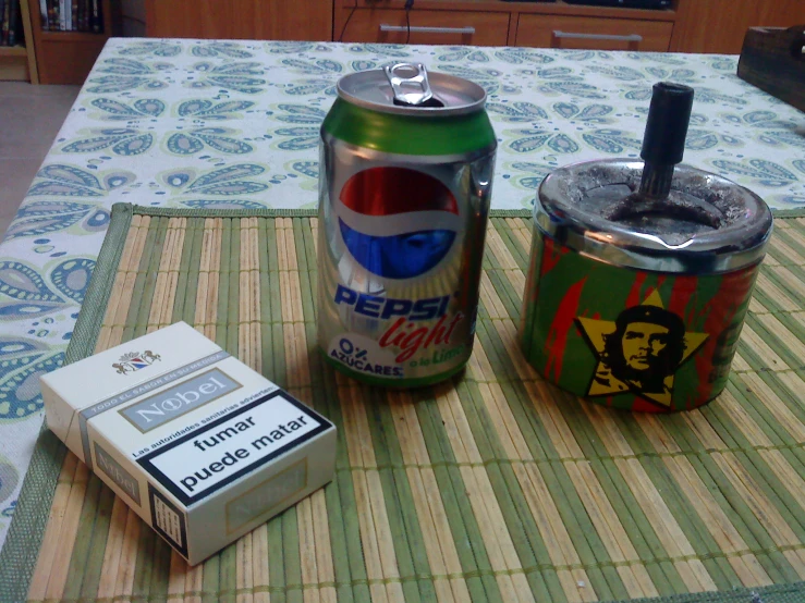 a cigarette and an empty can sitting on a table with the same theme on it