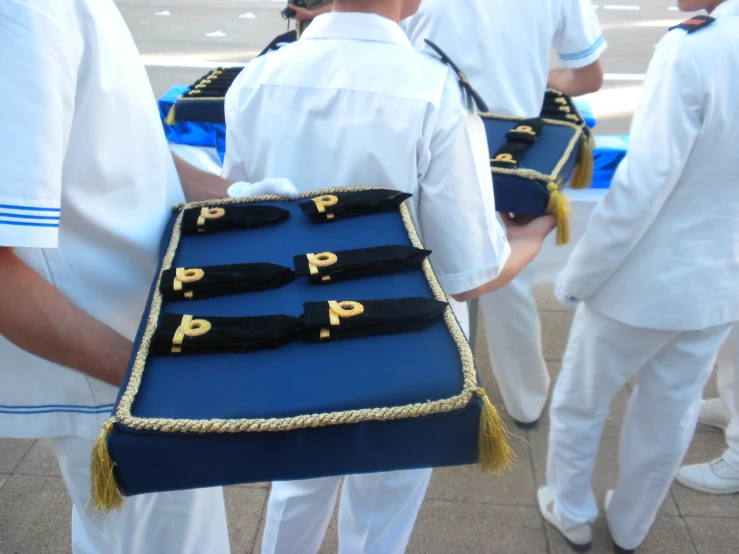 a person with a blue and yellow uniform holding a tray with sailors'ties