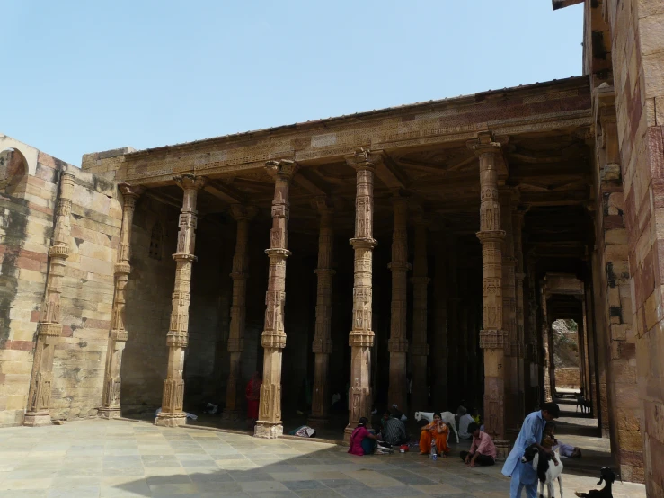 people sitting and standing in a building with large columns