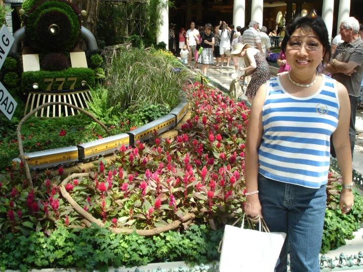 a woman smiling in front of flowers and bushes