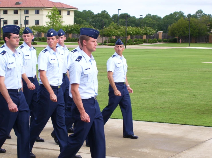 the uniformed men are marching along the sidewalk