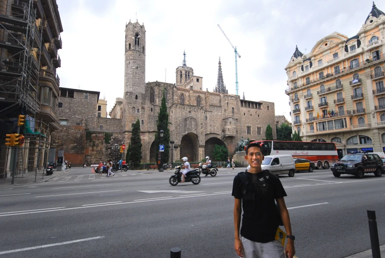 man posing in front of a building with cars and motorcycles