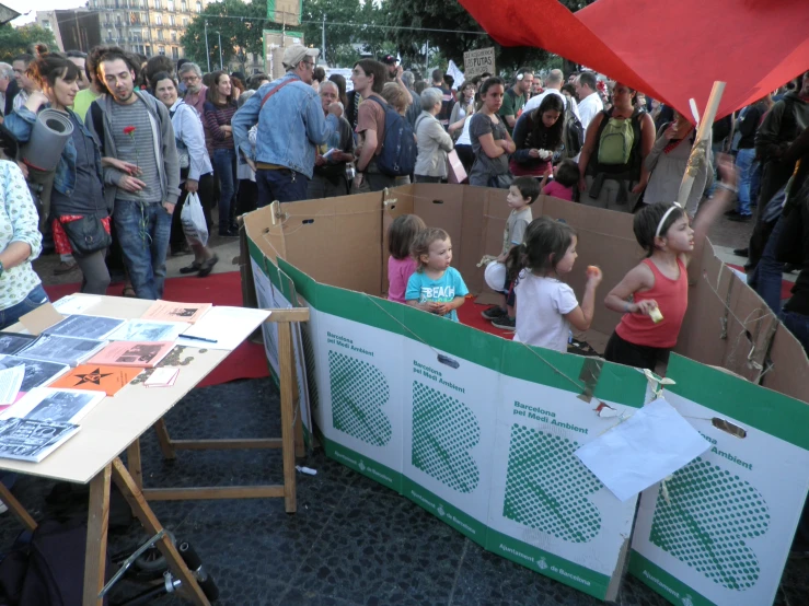 children sit in cardboard boxes with people around them