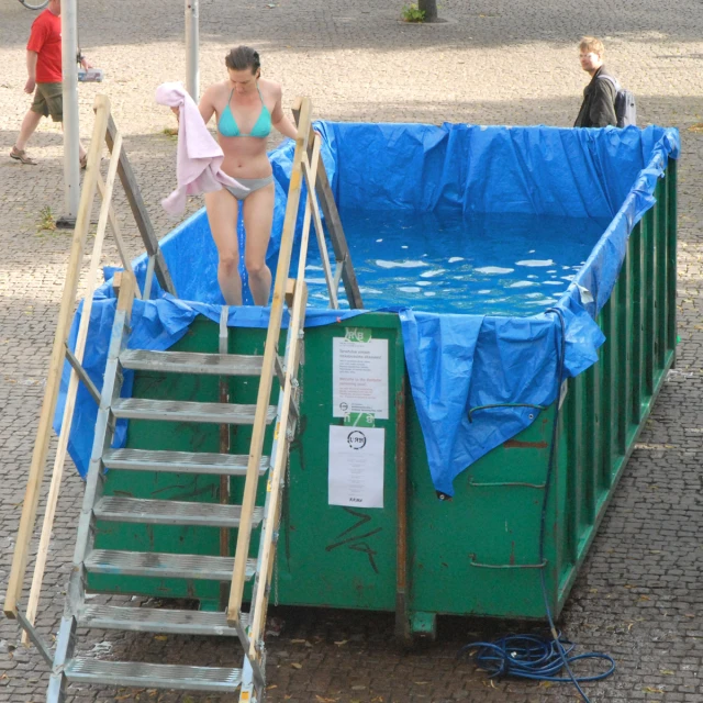 a woman in a bikini standing next to a green pool