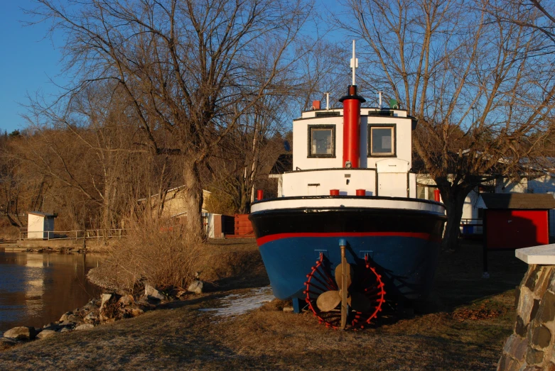 a big boat is sitting on land by some water