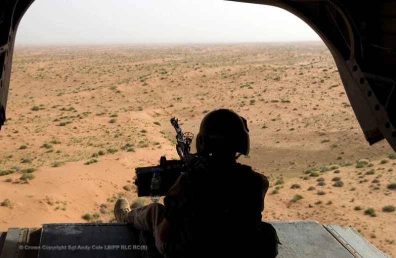 a man looking out of a helicopter at the desert