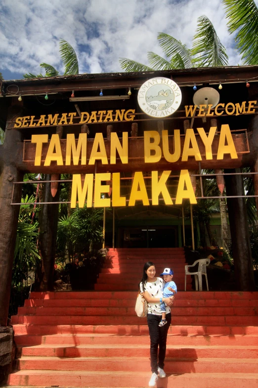 a man with his child under a sign in front of a tropical destination