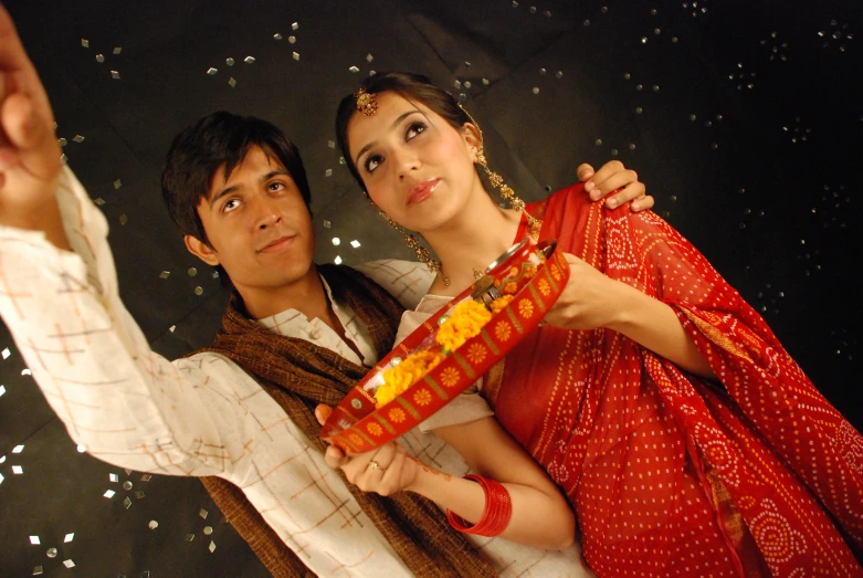 a couple dressed in traditional indian garb standing in front of an image of water