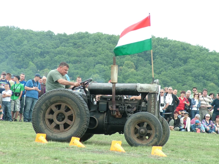 an old tractor in front of a crowd on the grass