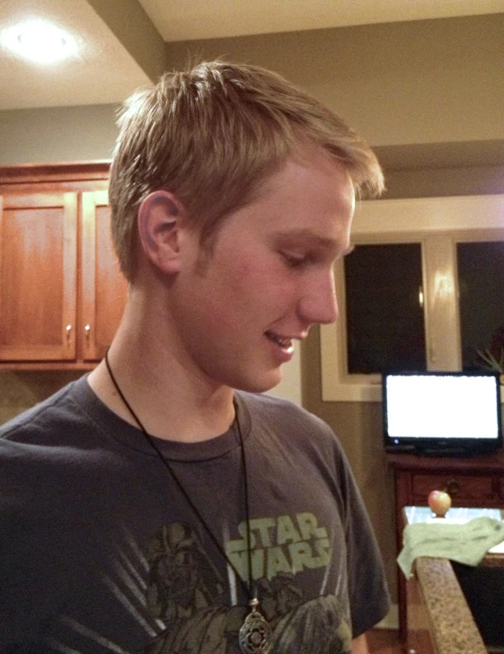 a young man wearing a star wars shirt looks at his cell phone