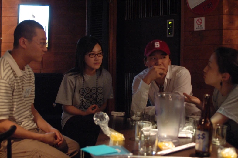 three people sitting at a table talking with one another