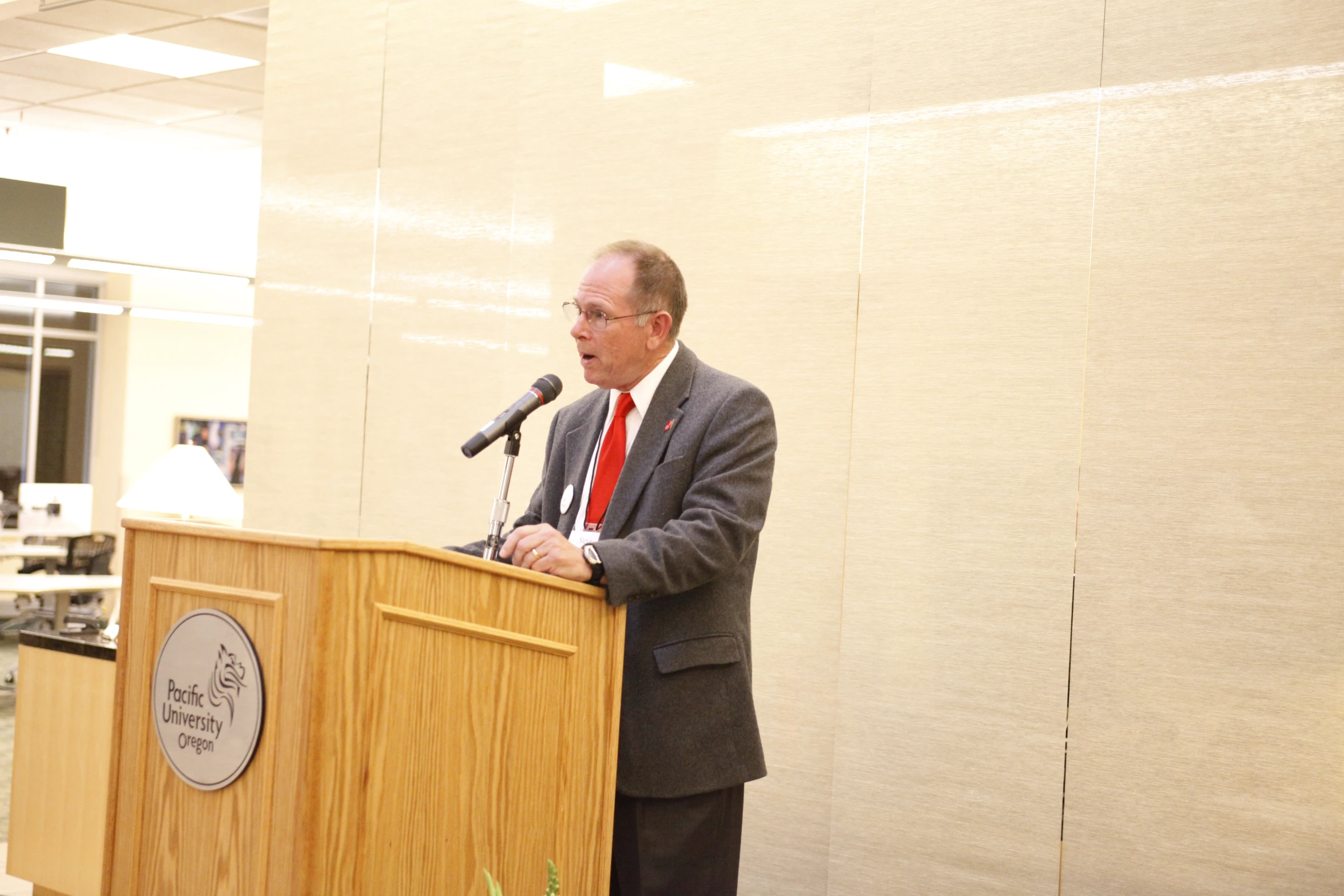 man in business attire speaking at a podium