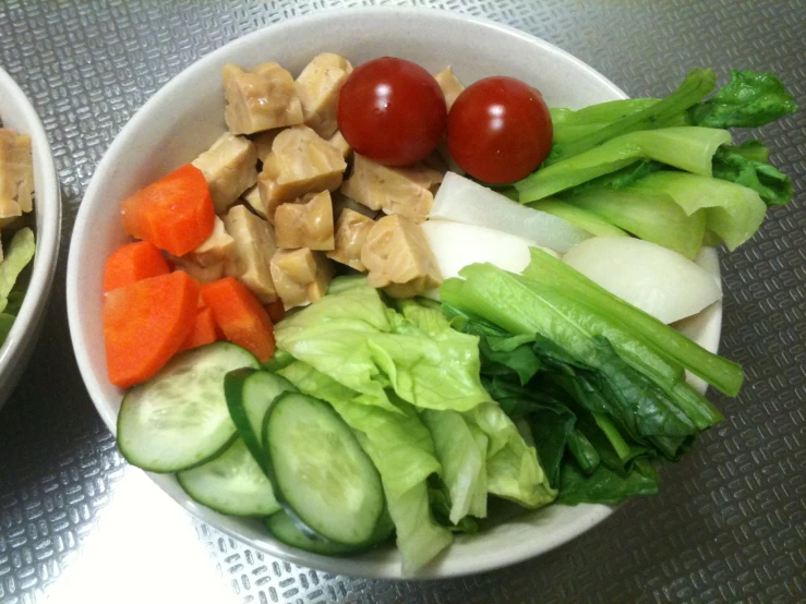 two white bowls holding vegetables, carrots and meat