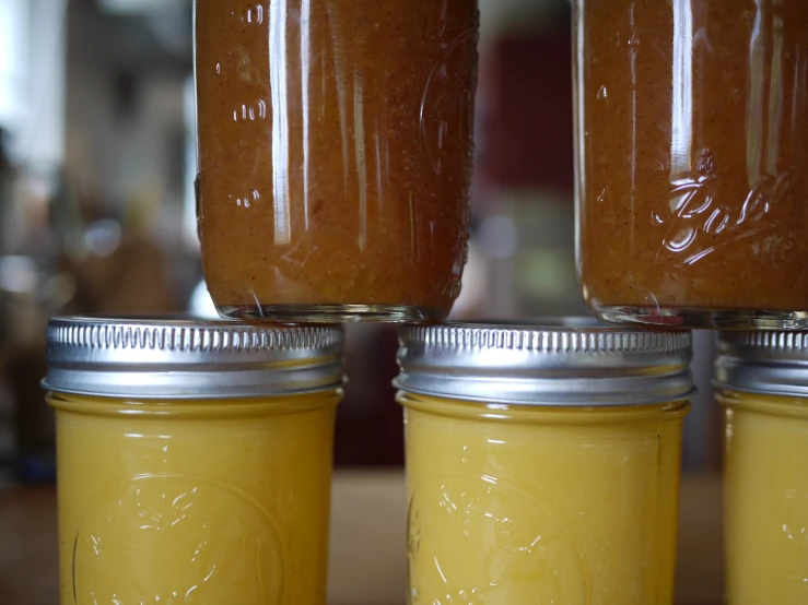 three jars filled with yellow liquid sitting on a counter