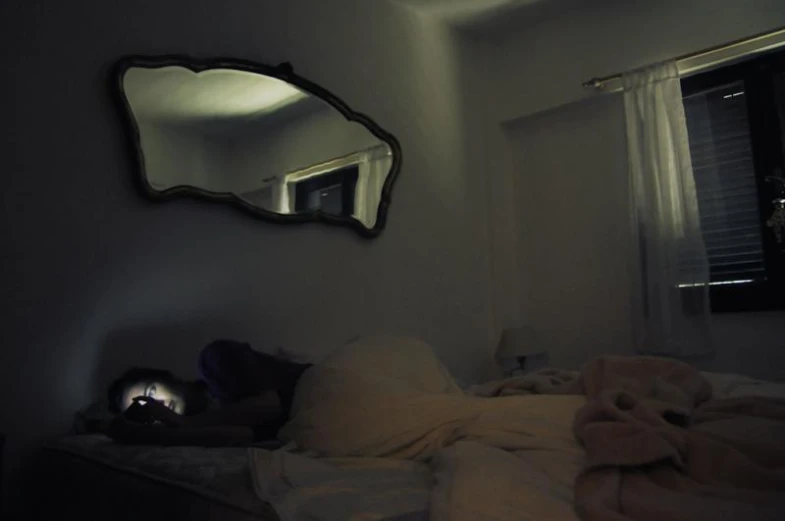 person laying down in a bed in front of a mirror