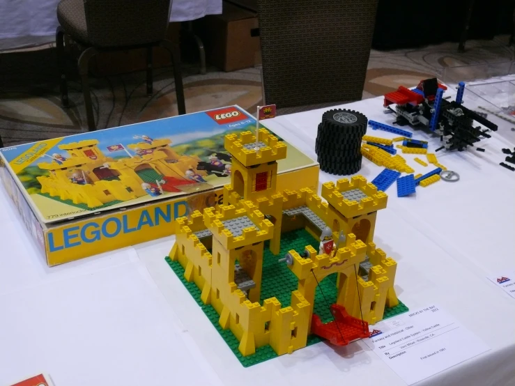 a table topped with lego castles next to a yellow box