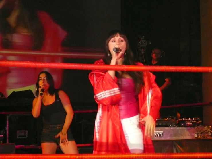 two women standing behind red ropes in an arena