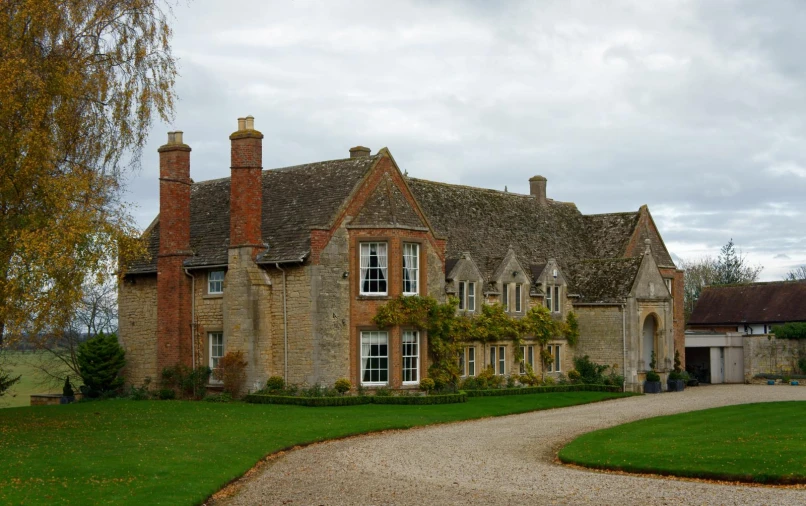 the path leading to a large brick house with a walkway running past it