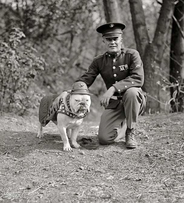 the man in the hat is crouching down with his dog