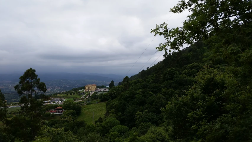 an area of green trees and mountains under a cloudy sky