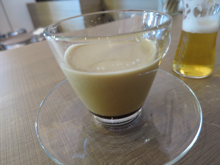 a glass of liquid sits on a plate next to two bottles