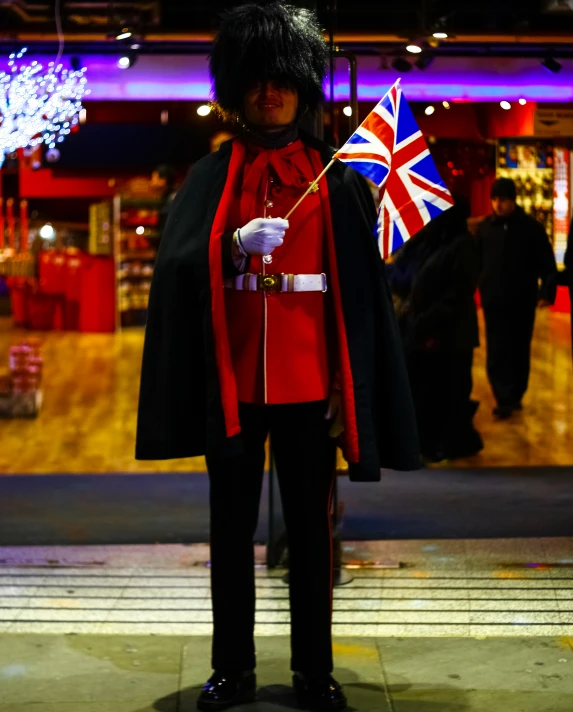 the british guard stands with a flag at night
