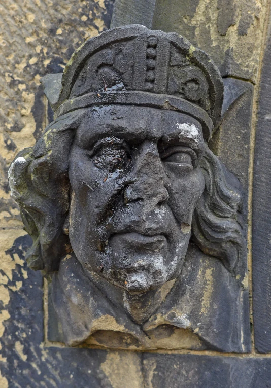 an old stone bust in front of a stucco wall