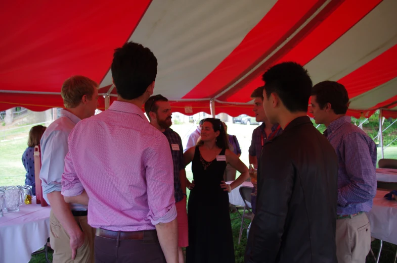 group of people having a conversation in front of red and white tent