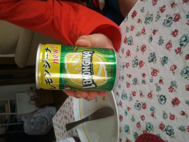 a person is holding a can of lemonade