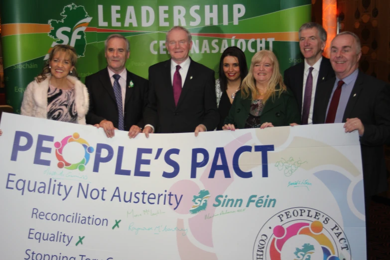 group posing for picture holding a banner advertising people'pact