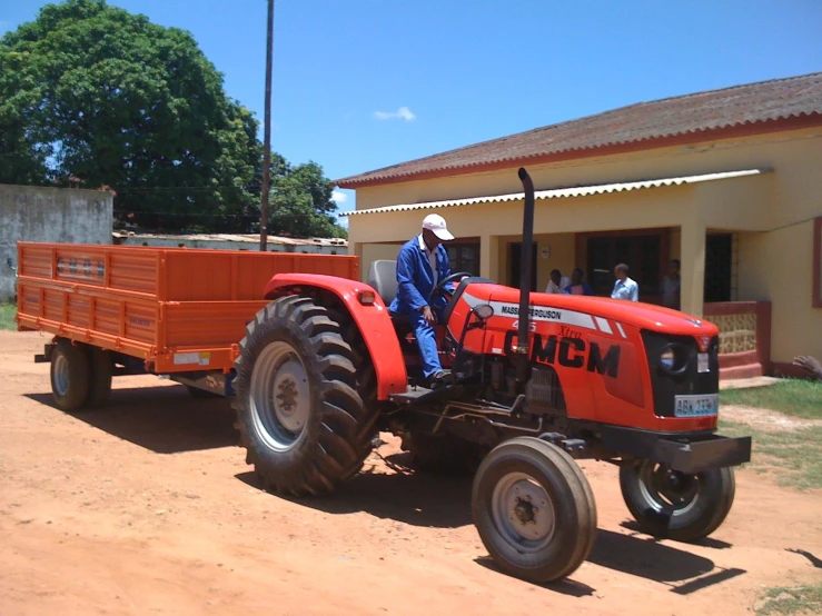 the man drives a small tractor with a trailer on it