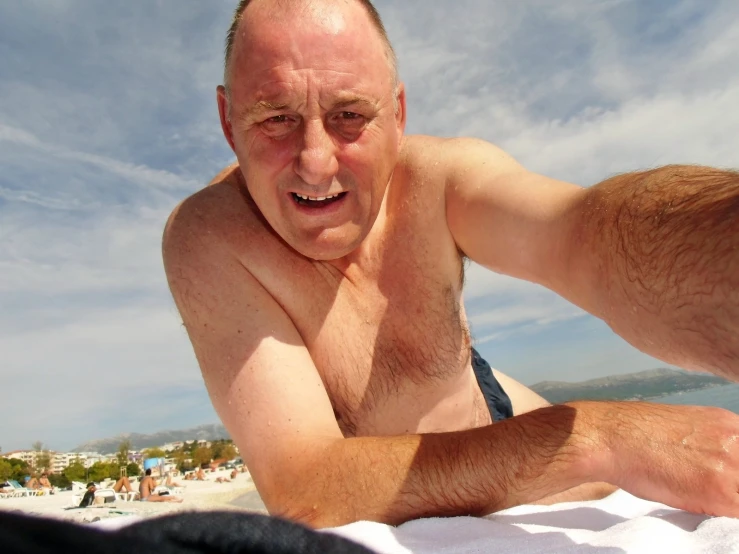 an older man laying on the sand in the sun