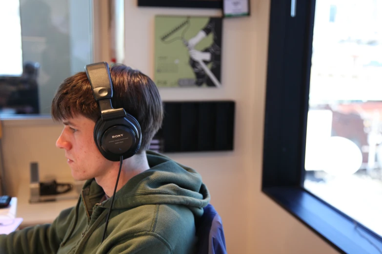 a young man with headphones on is looking at a monitor